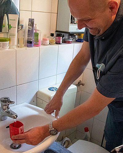 Christian Kurz lässt Wasser aus dem Wasserhahn in einen Messbecher fließen.